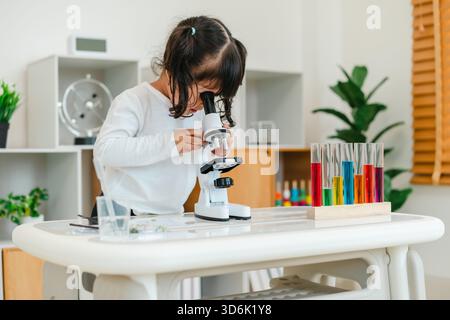 toddler girl scientist looking through a microscope. learning science Stock Photo
