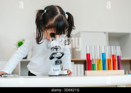 toddler girl scientist looking through a microscope. learning science Stock Photo