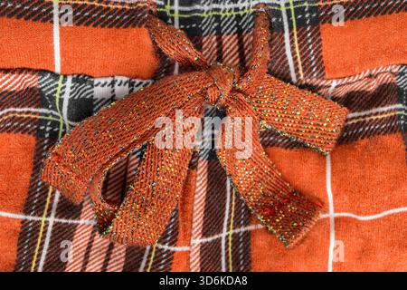 Tyed bow laces on orange color tartan fabric garment closeup as a background Stock Photo