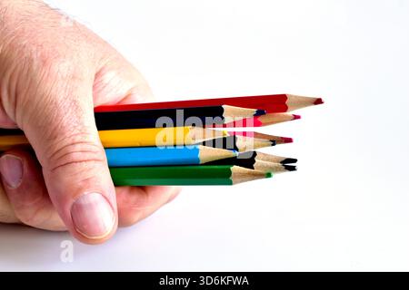 Colored pencils in a man's hand, which lies on a white background. Stock Photo