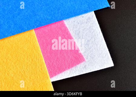 Thin A4 felt sheets of various shades lie on a black background. Stock Photo