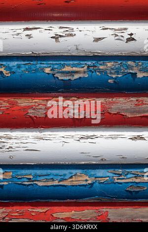Close-up of weathered red, white, and blue paint peeling off wooden boards, evoking rustic Americana and vintage charm. Stock Photo