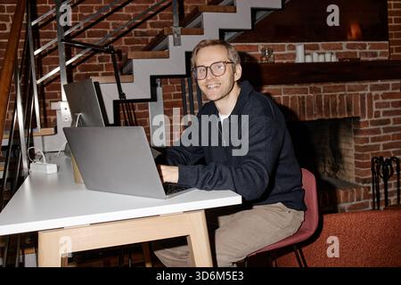 Portrait of Young Adult Caucasian Man Smiling While Working on Laptop Stock Photo