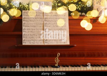 Music sheets, note and Christmas decor on piano. Bokeh effect Stock Photo