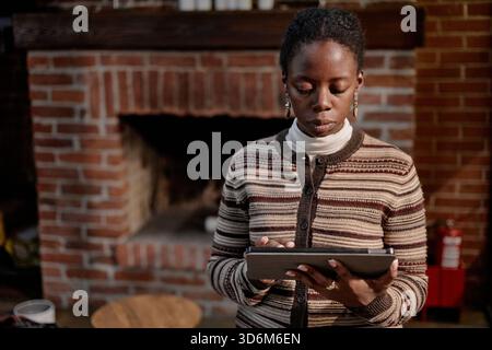 Young Adult Black Woman Using Digital Tablet in Modern Business Office Stock Photo