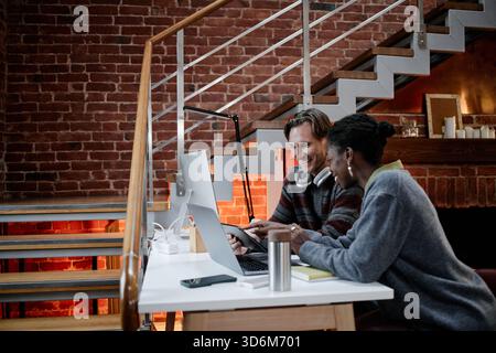Middle Aged Caucasian Man and Young Black Woman Analyzing Data on Office Laptop Stock Photo