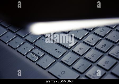 A silver laptop keyboard is viewed from above, partially obscured by a half-closed lid, while the "Enter" key is dramatically highlighted by a focused Stock Photo