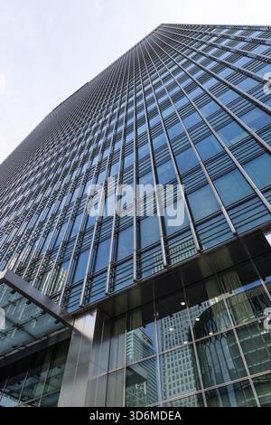 Modern glass skyscraper with reflective facade in downtown business district Stock Photo