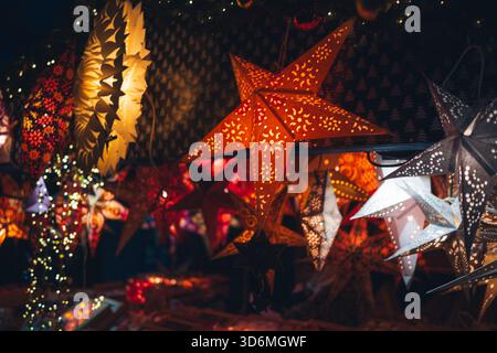 Illuminated paper star lanterns hanging in a dark setting. Close up shot, no people Stock Photo
