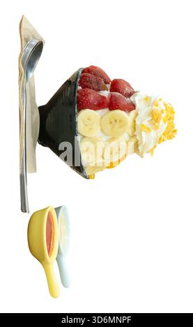 A set of Korean Bingsu in small black bowl with several fruits topping and red sauce with sweeten condensed milk in mini plastic bowls are isolated on Stock Photo