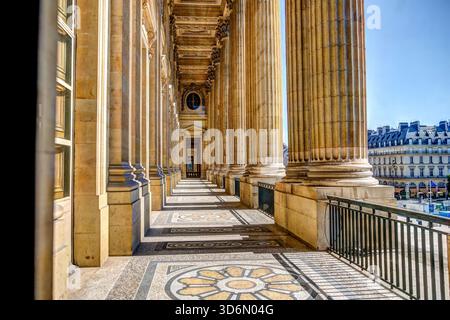 Colonnade of the Louvre Museum in Paris photographed in bright morning light, with tall classical columns and patterned stone flooring. Stock Photo
