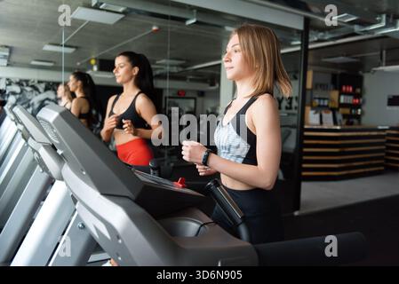Two active women doing cardio on treadmill at gym Stock Photo