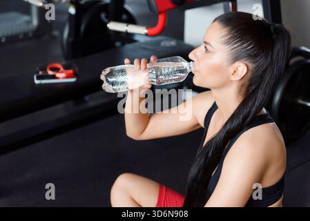 Sporty woman drinking water while relaxing after workout Stock Photo