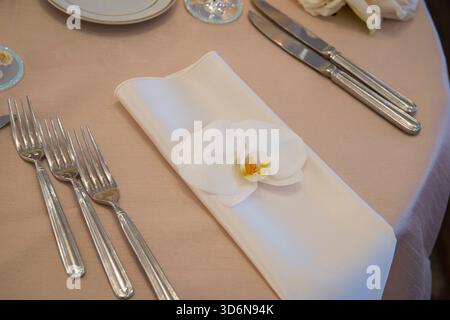 Elegant Table Setting with White Orchid on Folded Napkin Stock Photo
