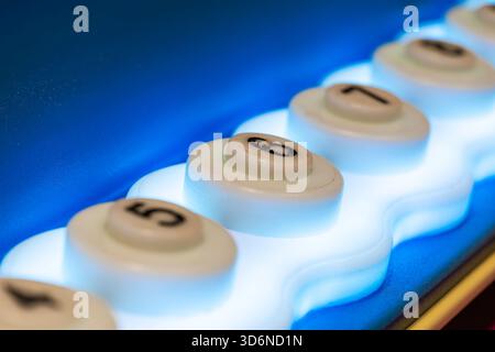 Blue backlit panel with white buttons with black numbers and focus on button 6 Stock Photo