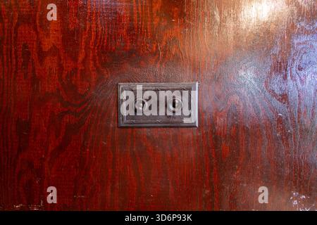 Photo of an extremely olds light switch from the 1940's in the UK made out of brass on a wooden wall Stock Photo