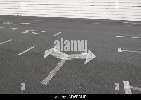 Directional Arrow Painted on Asphalt in Empty Parking Area Stock Photo