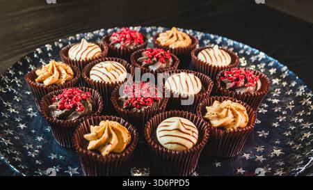Plate full of beautiful colorful chocolate mini cupcakes with vibrant frosting. Perfect for parties, celebrations and dessert tables. Sweet and deligh Stock Photo