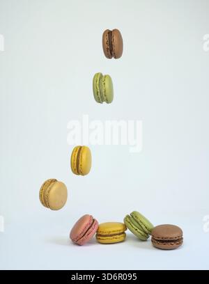 Colored macaroons falling in a row on a white table with copy space Stock Photo
