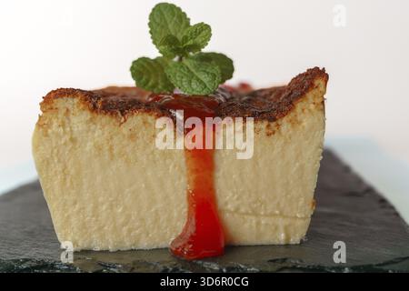 Cheesecake with strawberry jam and mint leaves on a black board Stock Photo