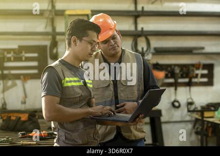 Carpentry Workshop manager using the computer to teach a worker. Carpentry foreman showing computer to colleague in the workshop Stock Photo
