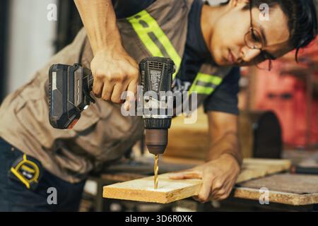 Cabinetmaker working on a piece of furniture with a drill in the carpentry shop. Close-up of a construction man using a drill Stock Photo