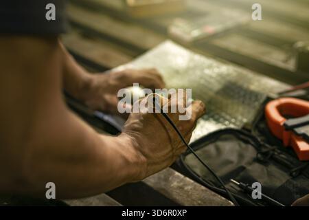 Close-up of a man using a soldering iron on an electronic circuit board on a table Stock Photo