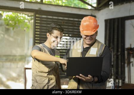 Carpentry boss showing computer to colleague in the workshop. Carpentry Workshop manager using the computer to teach a worker Stock Photo