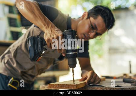 Close-up of a construction man using a drill. Cabinetmaker working on a piece of furniture with a drill in the carpentry shop Stock Photo