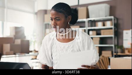 Black woman, laptop and stress for dropshipping, logistics or documents with distribution error in office. African person, paperwork and admin with Stock Photo