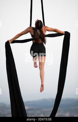 Young woman performing on aerial silk outdoors Stock Photo