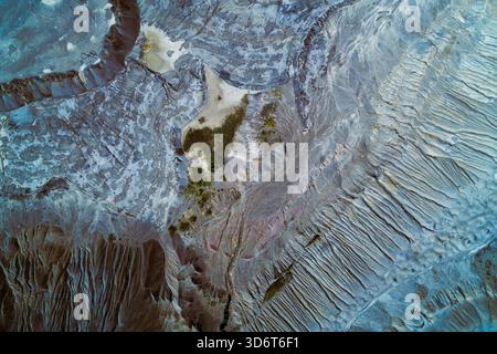 Top-down aerial photography showing a massive industrial tailings pond or slag dump. Abstract geomorphic patterns in toxic blue-gray colors, illustrating severe environmental damage. Stock Photo