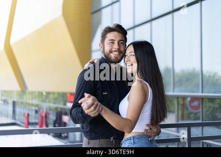 A man and a woman are smiling and holding hands while standing in a dance pose Stock Photo