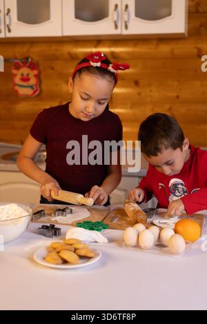 The children are baking Christmas cookies together in the kitchen Stock Photo