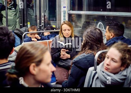 Paris, France - March 2025: A woman is absorbed in a book while riding the subway in Paris's 15th arrondissement. Stock Photo