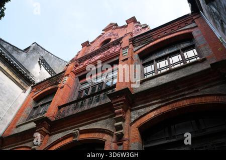 Historic European Style Red-Brick Architectural Facade with Ornate Details Between Two Chinese Style Buildings, Captured from a Low-Angle View Stock Photo
