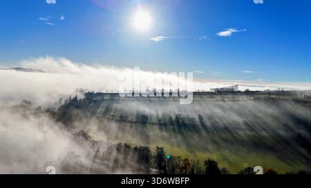 Autumn morning mist rising from the River Ericht in Blairgowrie, with warm sunlight streaming through the trees and old mill buildings along the river Stock Photo