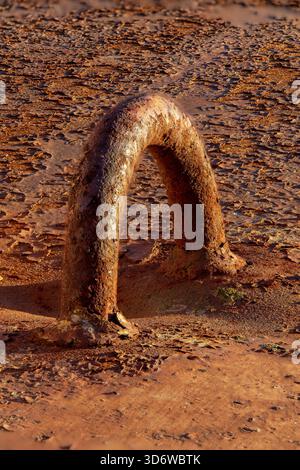 Rusty metal loop emerging from corroded surface, detailed industrial decay with warm colors and textured patina. Stock Photo