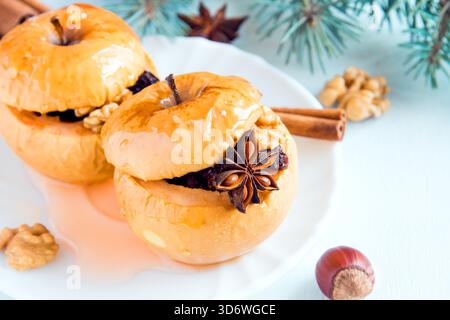 Christmas baked apples stuffed with dried fruit, nuts, cinnamon, anise and honey on white plate close up Stock Photo