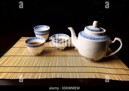 Elegant Chinese tea set with teapot and four cups, two filled with tea. Ideal for themes of culture, tradition, ceremony, and relaxation. Stock Photo