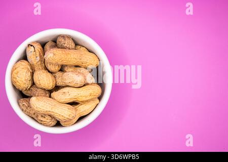 Monkey nuts arranged in a white dish on a plain background, suitable for food, snack, and ingredient themes. Stock Photo