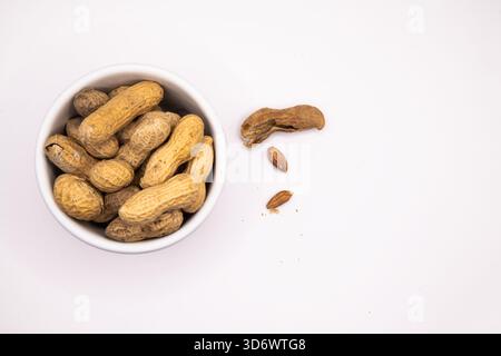 Monkey nuts arranged in a white dish on a plain background, suitable for food, snack, and ingredient themes. Stock Photo