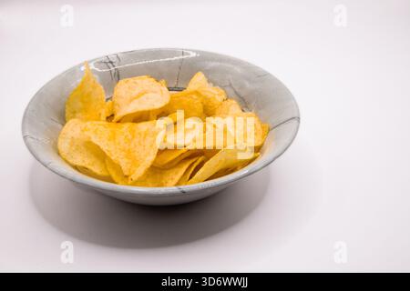 Crisps served in a grey bowl on a plain white background, suitable for snack and food imagery. Stock Photo