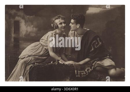 A vintage, sepia-toned postcard depicts a young couple in classical or ancient attire, holding hands and gazing at each other in a stylized, painted b Stock Photo