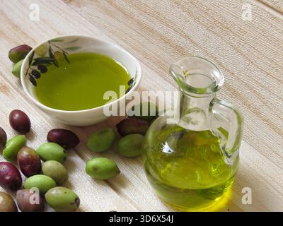 Natural, eco-friendly olive oil in Greece with a bottle and small dish, surrounded by fresh green and black olives on the table. Stock Photo