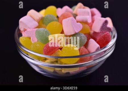 Candies on black in a transparent bowl on a black background. Close-up. Stock Photo