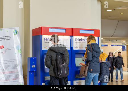 Passengers at Hannover Hauptbahnhof use ticket machines beneath large 'Abfahrt' departure boards. Stock Photo
