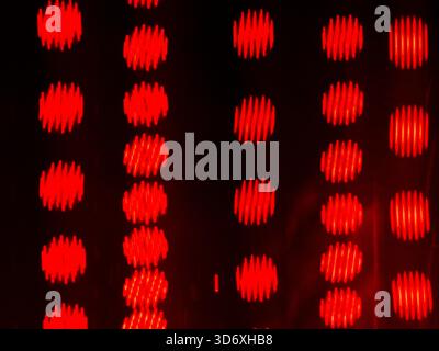 Red glowing circles with a textured zigzag pattern creating an abstract background, appearing on a dark backdrop and forming a grid, providing a vibra Stock Photo