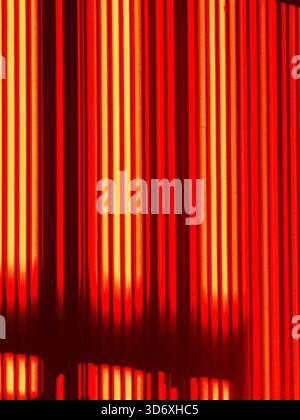 Bright warm light reflecting from a surface, forming a graphic composition with vertical lines of red and orange against a dark background, evoking en Stock Photo
