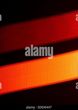 Radiating diagonal bands of pixelated red orange light and gradient glow on a dark backdrop, creating vibrant, geometric texture with dynamic motion a Stock Photo